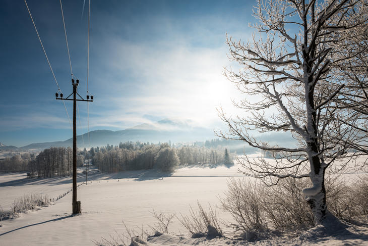 Vinterdag med elektriske linjer, sol og fjell i bakgrunnen