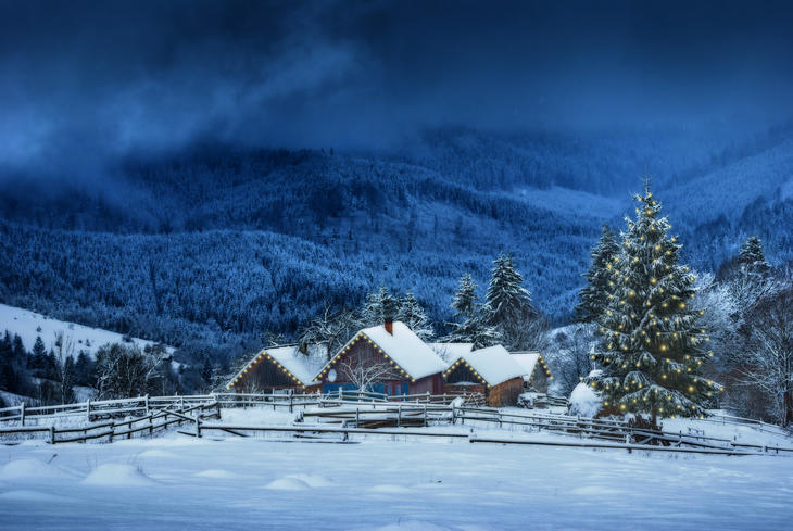 Julepyntet hus med snø, om kvelden i fjellet