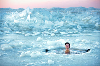 Mann isbader på frossen dam