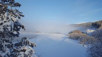 Landskapsbilde av Lalmsvatnet dekket av snø en kaldt vinterdag.