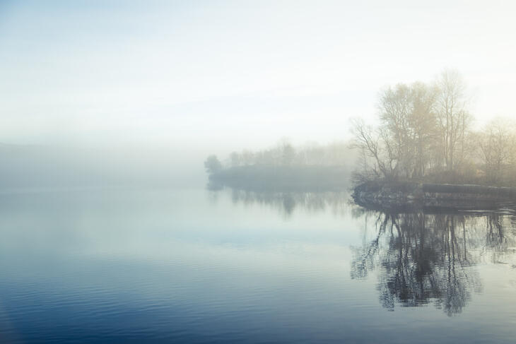 En tåkete høstmorgen ved innsjøen.
